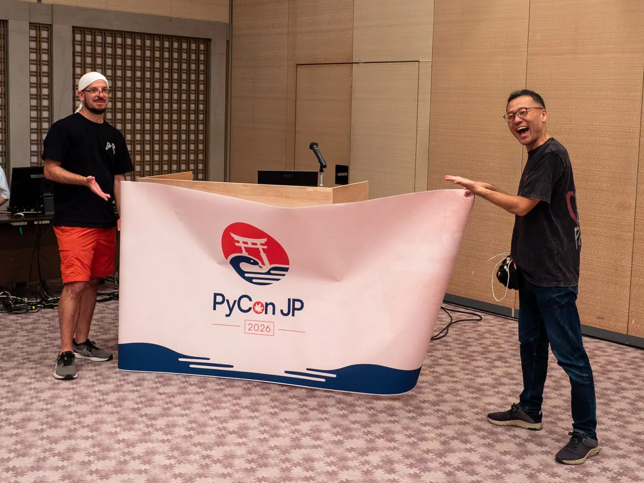 演台に PyCon JP の幕を取り付けるスタッフ